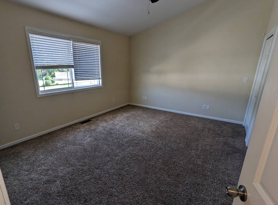 Empty bedroom with spotless plush carpet and streak-free window after move-out cleaning in Rochelle IL