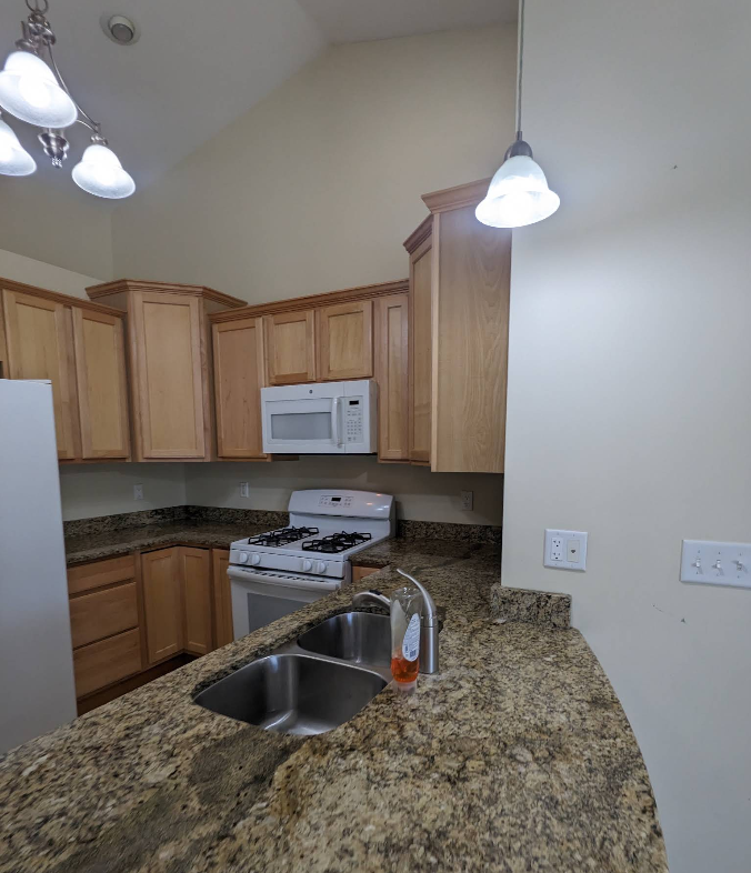 Sparkling kitchen with granite counters, wood cabinets, and stainless sink after deep cleaning in Rochelle IL